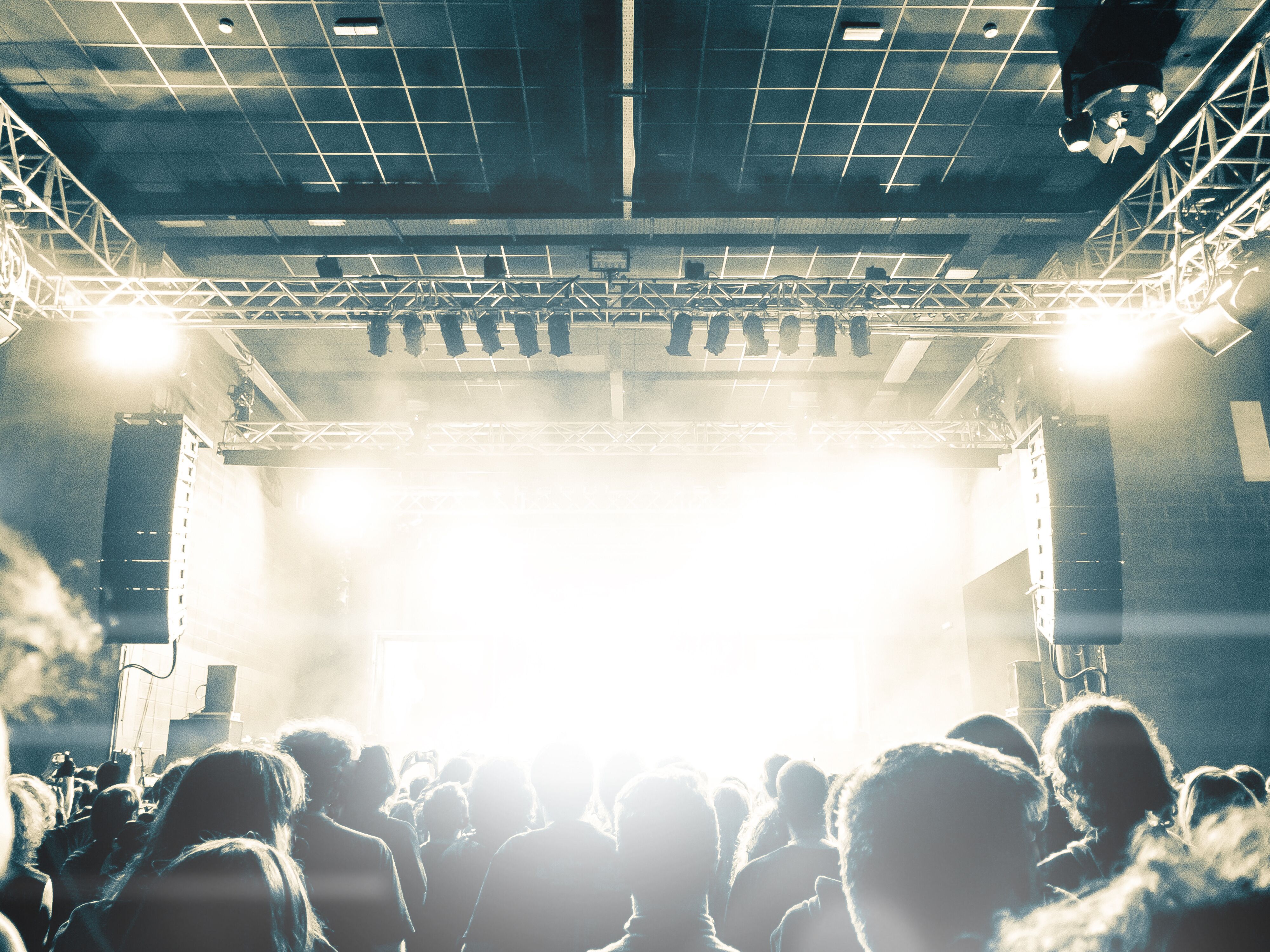 menschen-stehen-vor-b&uuml;hne-mit-hellen-scheinwerfern